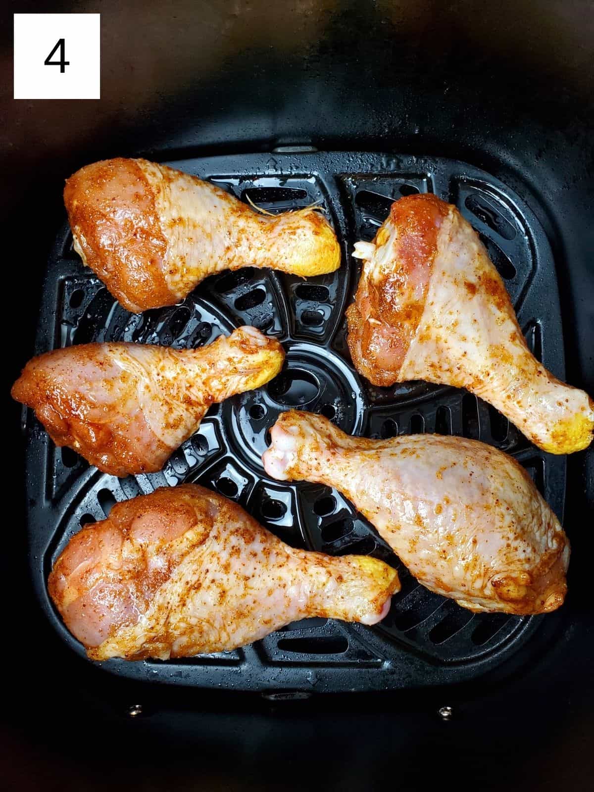 seasoned chicken legs on a basket of pre-heated air fryer.