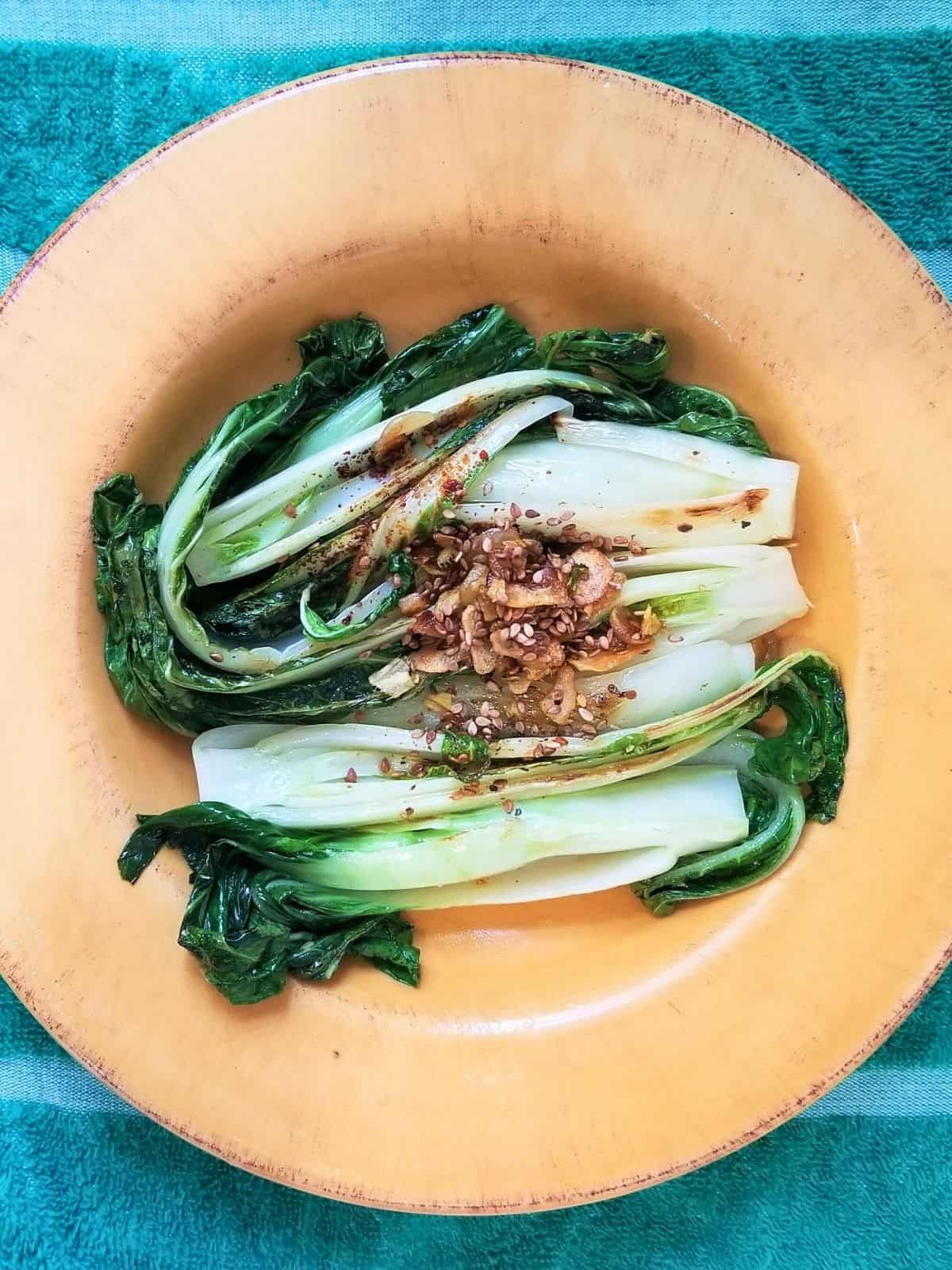 cooked ginger garlic bok choy on a yellow plate.