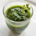garlic herb sauce in a glass, topped with fresh herbs.