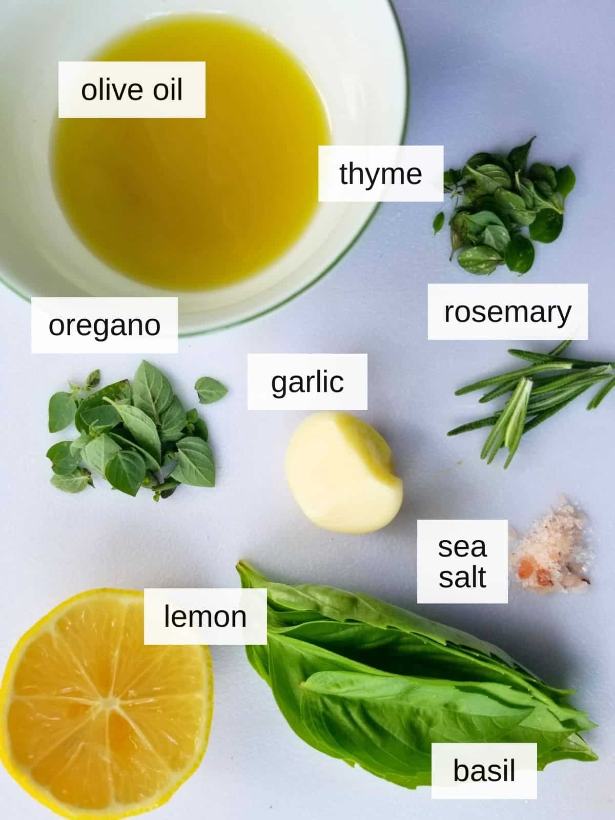 ingredients for garlic herb sauce, including sea salt, rosemary, thyme, olive oil. garlic. basil leaves, lemon juice, and oregano.