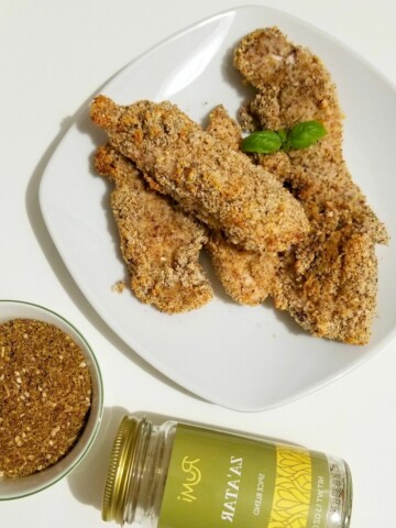 grain-free chicken tenders on a plate and a jar of za'atar spice blend.