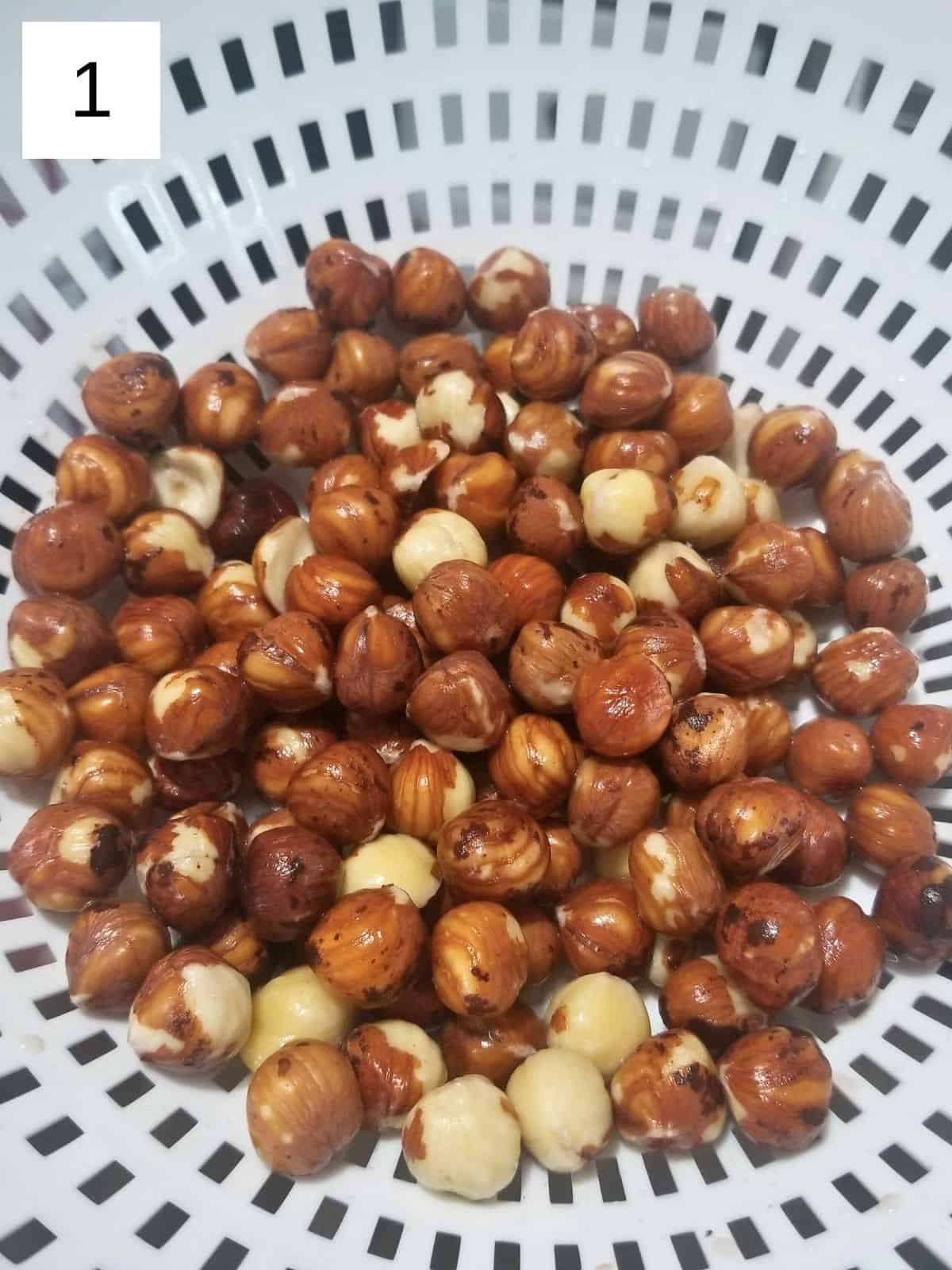 draining and rinsing off the soaked hazelnuts in a white plastic strainer.