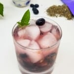 mocktail of lavender and blueberries with ice in a glass.
