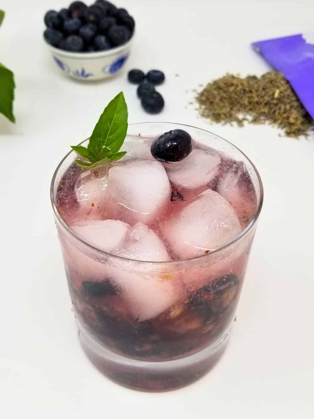 mocktail of lavender and blueberries with ice in a glass.