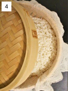 sticky rice wrapped in cheesecloth in a steamer basket on top of a pot of boiling water.