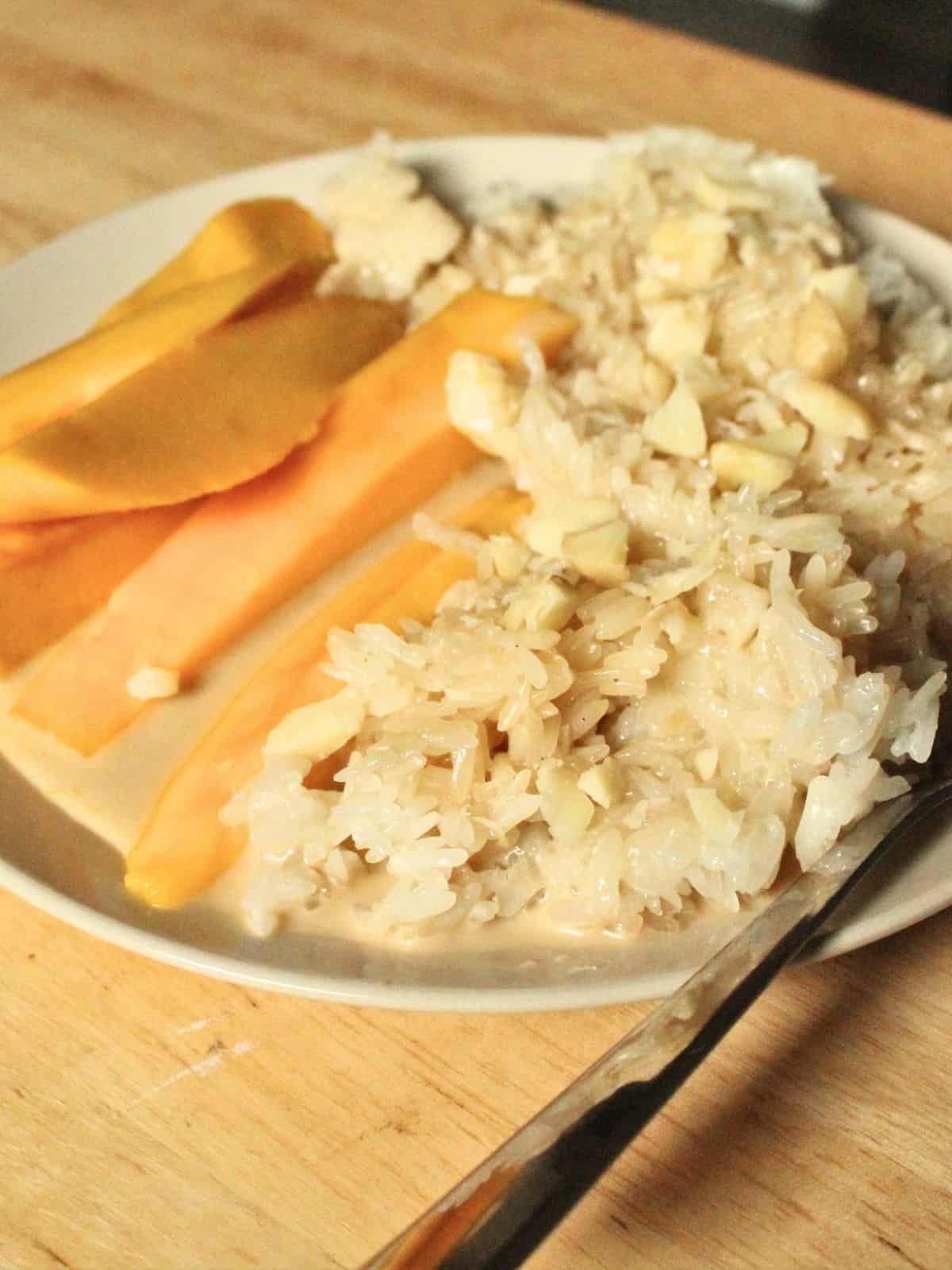 mango sticky rice with nuts on a plate.