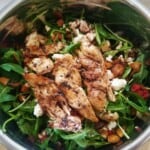 vegetable salad with chicken and pomegranate sumac salad dressing in a mixing bowl.