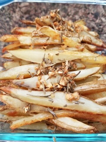 baked French fries, seasoned with rosemary garlic, in a glass container.
