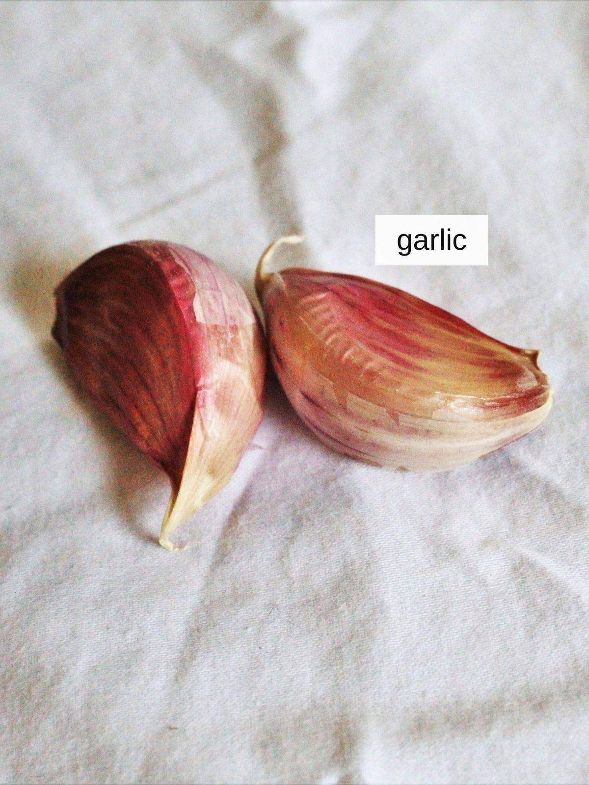 two raw garlic cloves on a white cloth.