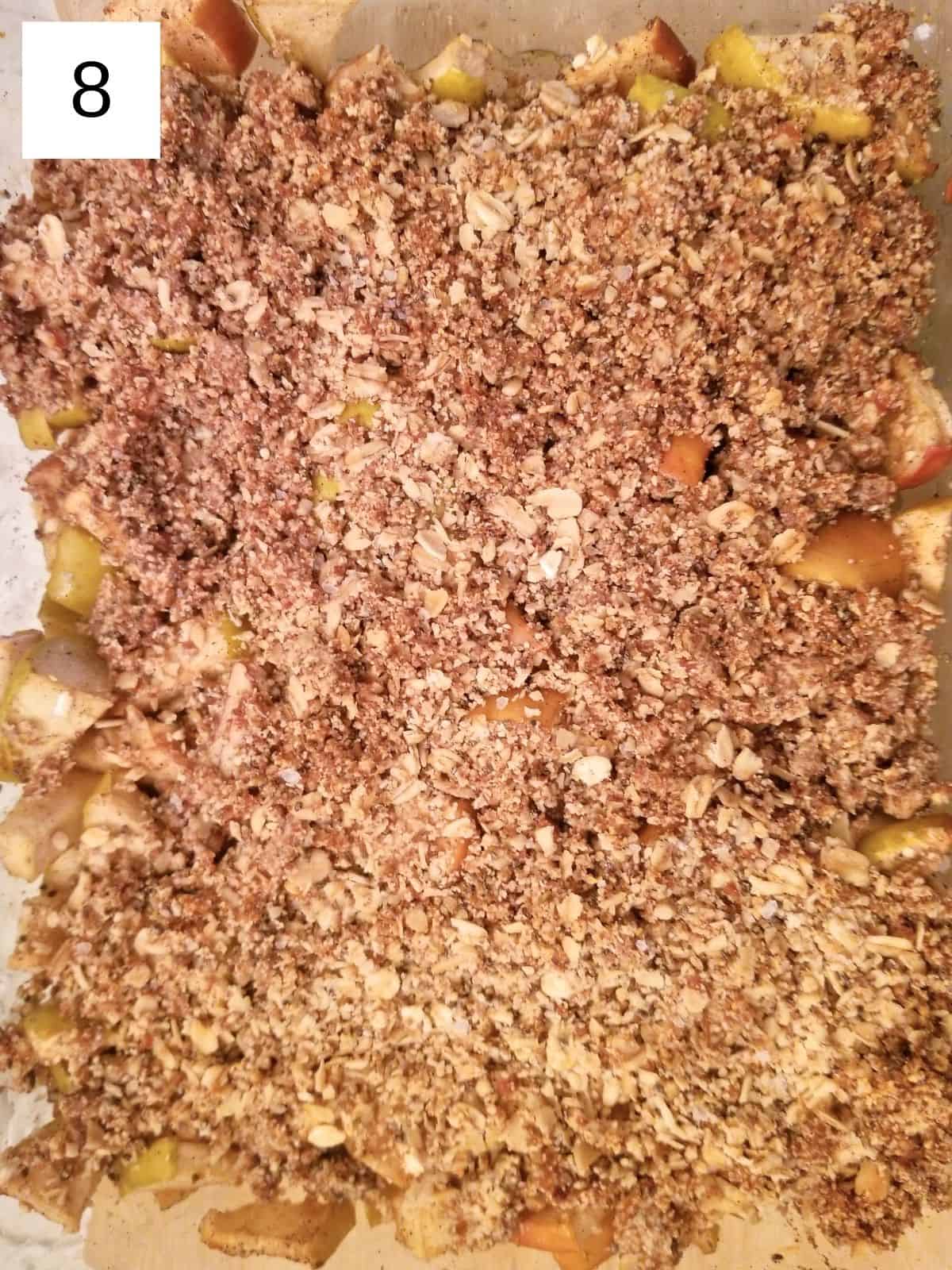 baked apples, topped with an oat mixture, on a baking dish.