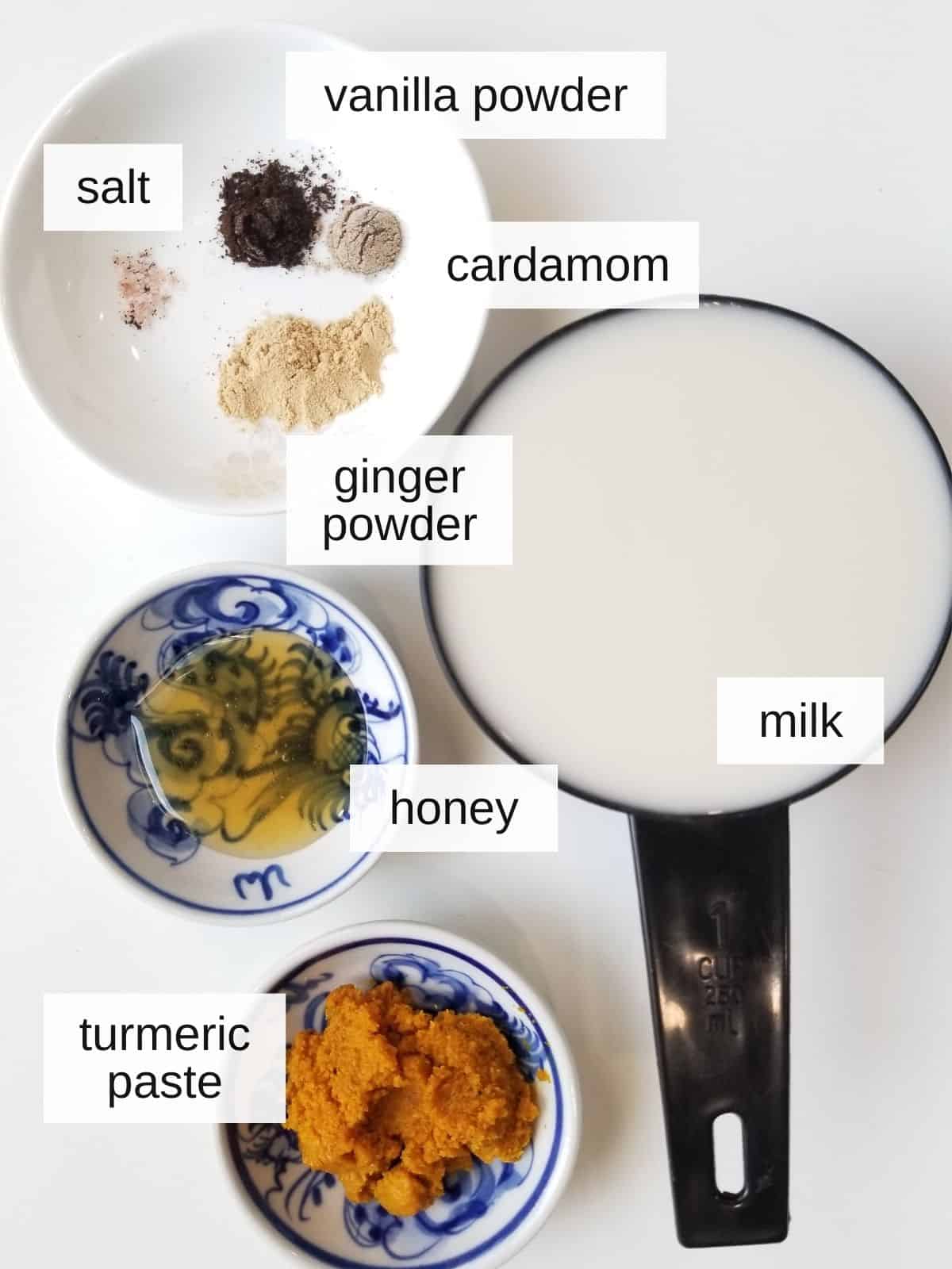 golden/turmeric milk latte recipe ingredients, including vanilla powder, cardamom, salt, ginger powder, milk, honey, and turmeric paste.