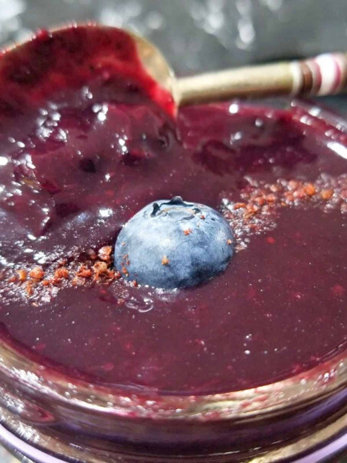 blueberry vanilla jam in a glass container with a piece of blueberry on top.
