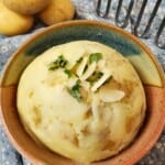 cooked mashed potatoes in a bowl with a garnish on top.