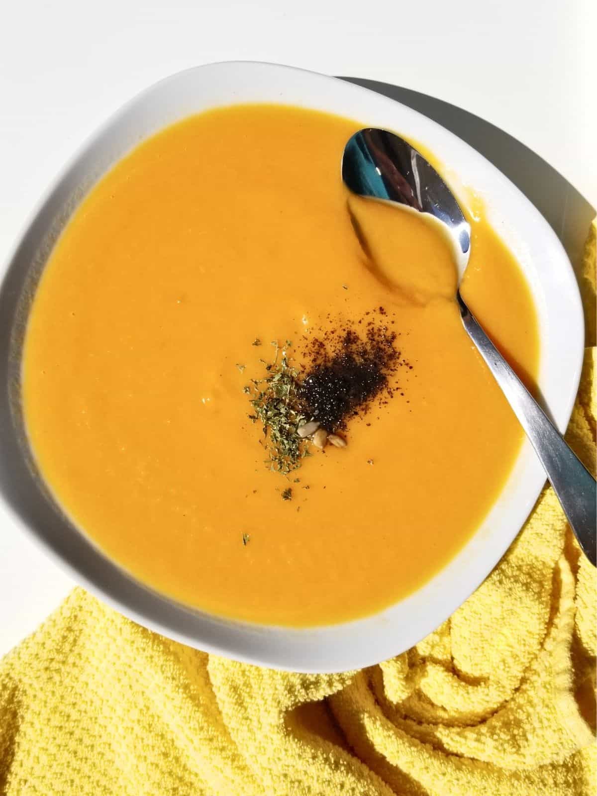 butternut squash soup, sprinkled with some herbs, in a bowl.