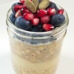 overnight oats, topped with fresh fruits and seeds, in a glass jar.
