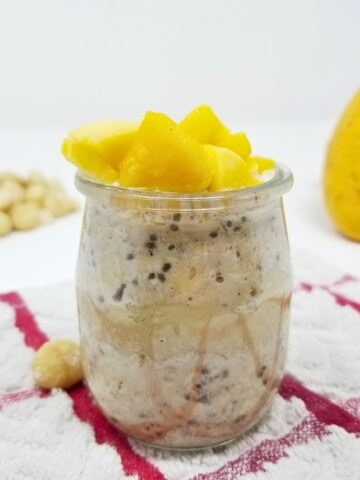 overnight oats, topped with fresh mangoes, in a glass jar.