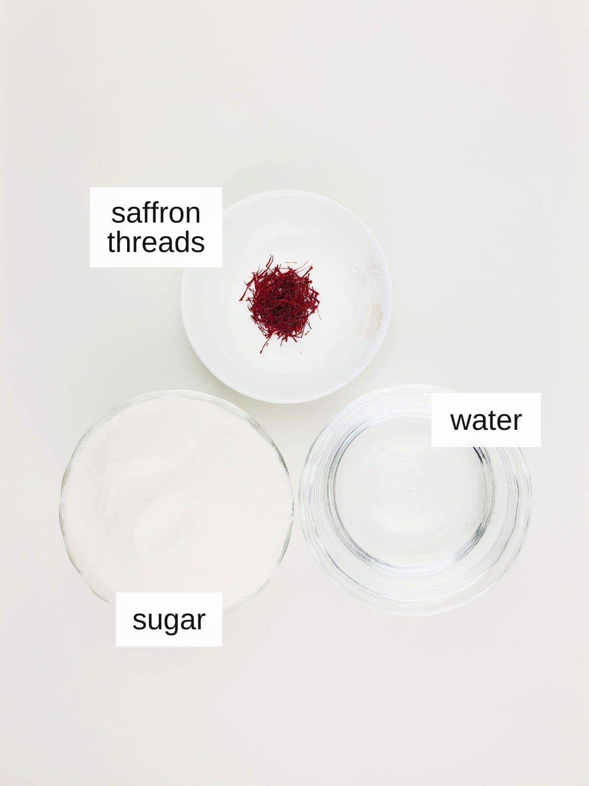 ingredients for saffron syrup, including saffron threads, sugar, and water.