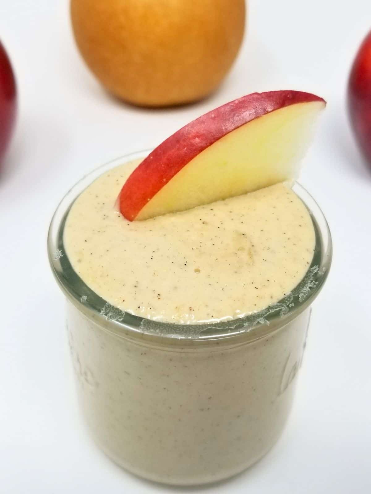 sweet tahini dipping sauce, topped with fresh slice of apple, in a glass container.