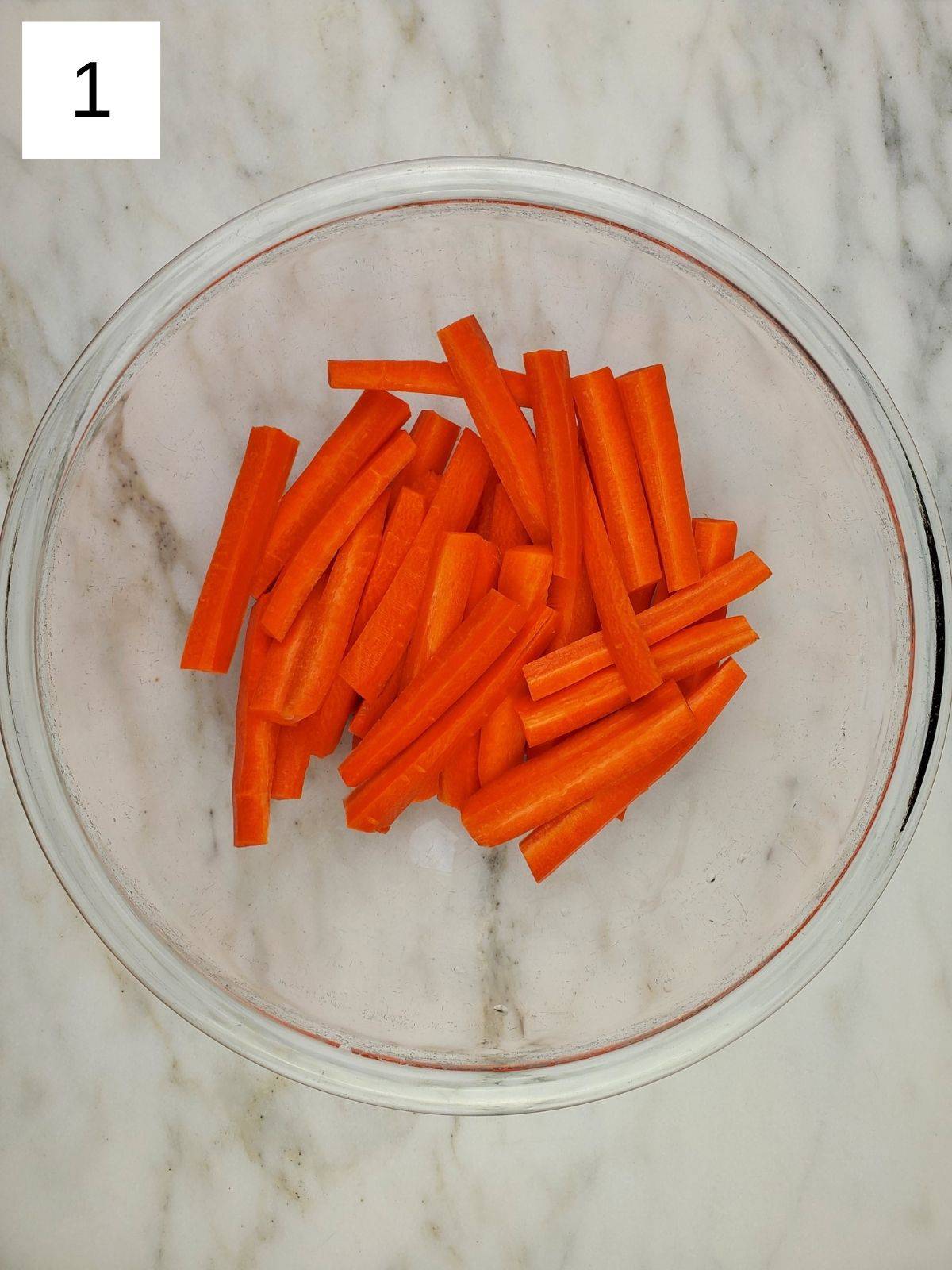sliced carrots in a large glass bowl.