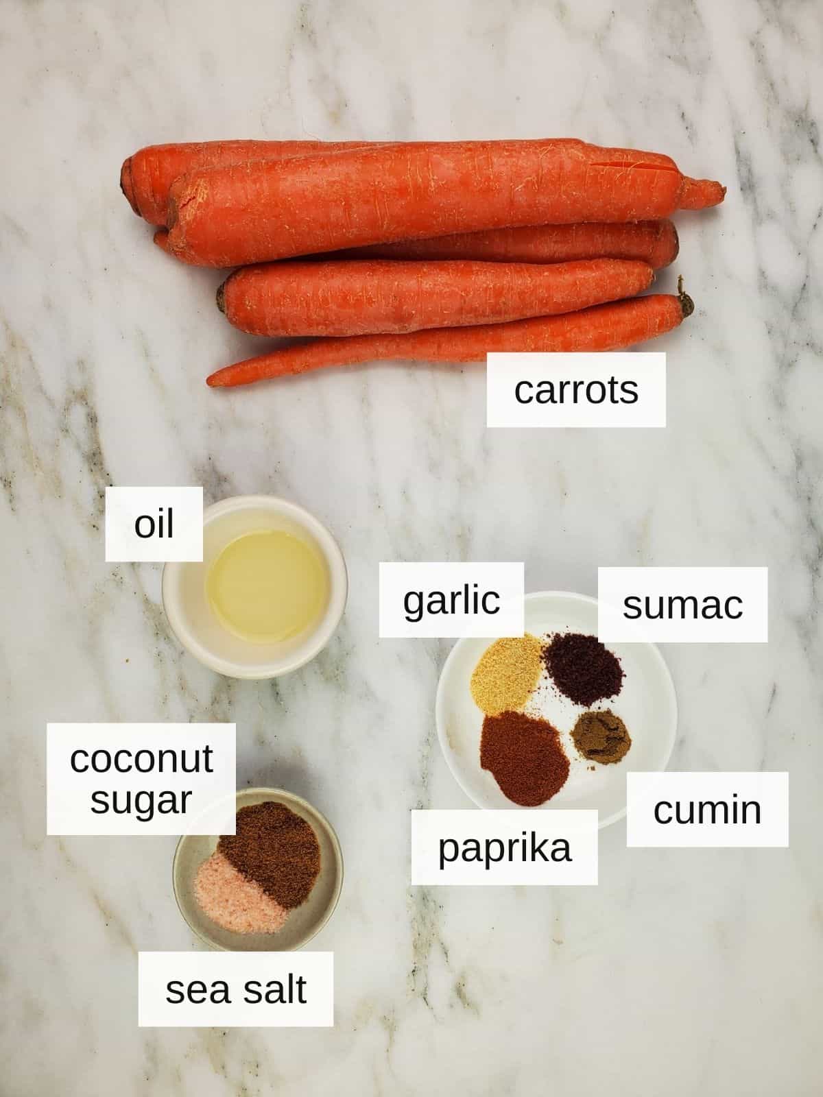 ingredients for making carrots fries in air fryer, including carrots, oil, garlic, sumac, coconut sugar, paprika, cumin, and sea salt.