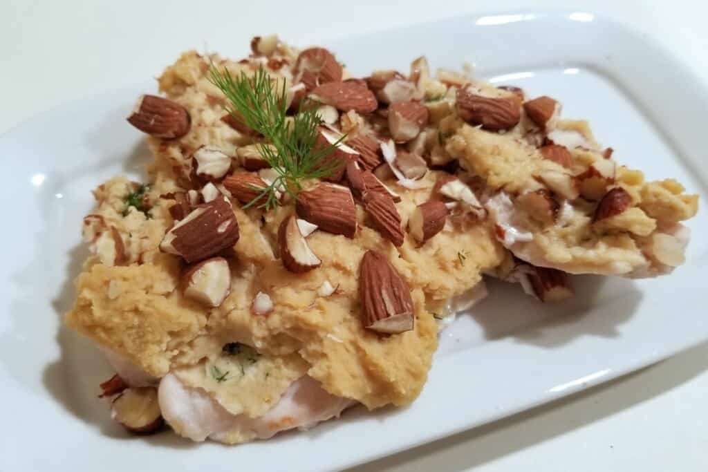 baked hummus chicken with chopped almonds on top.