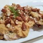 baked hummus chicken with chopped almonds on top.