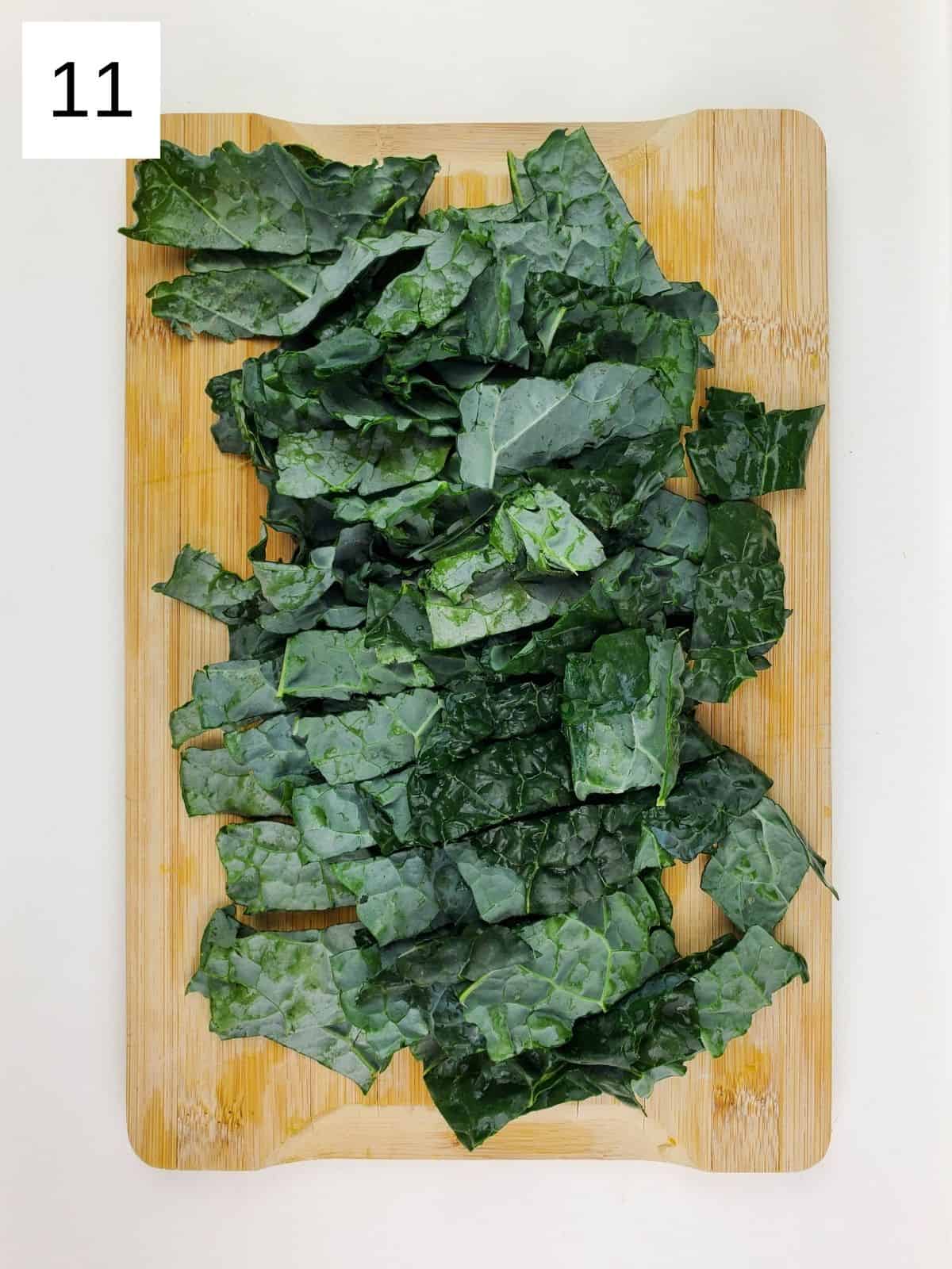 chopped kale leaves on a wooden cutting board.