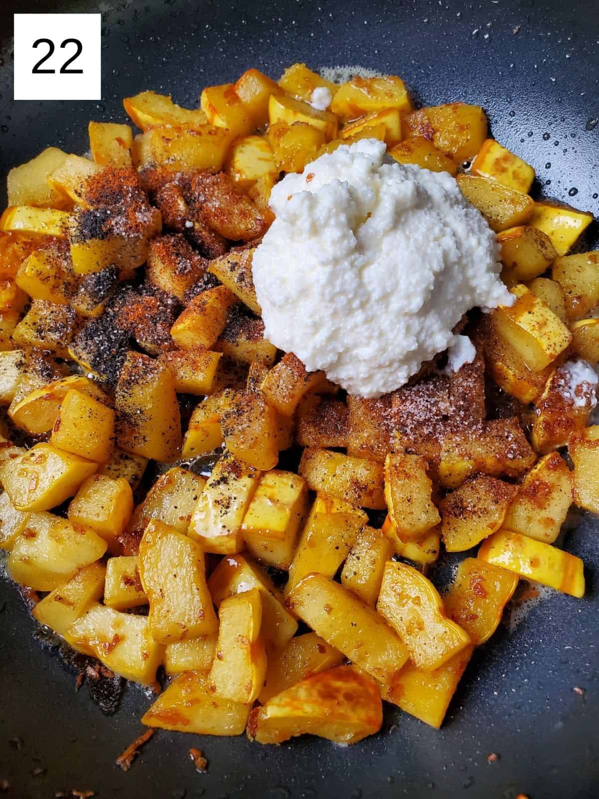 browned delicata squash cubes with seasonings and ricotta cheese on top.
