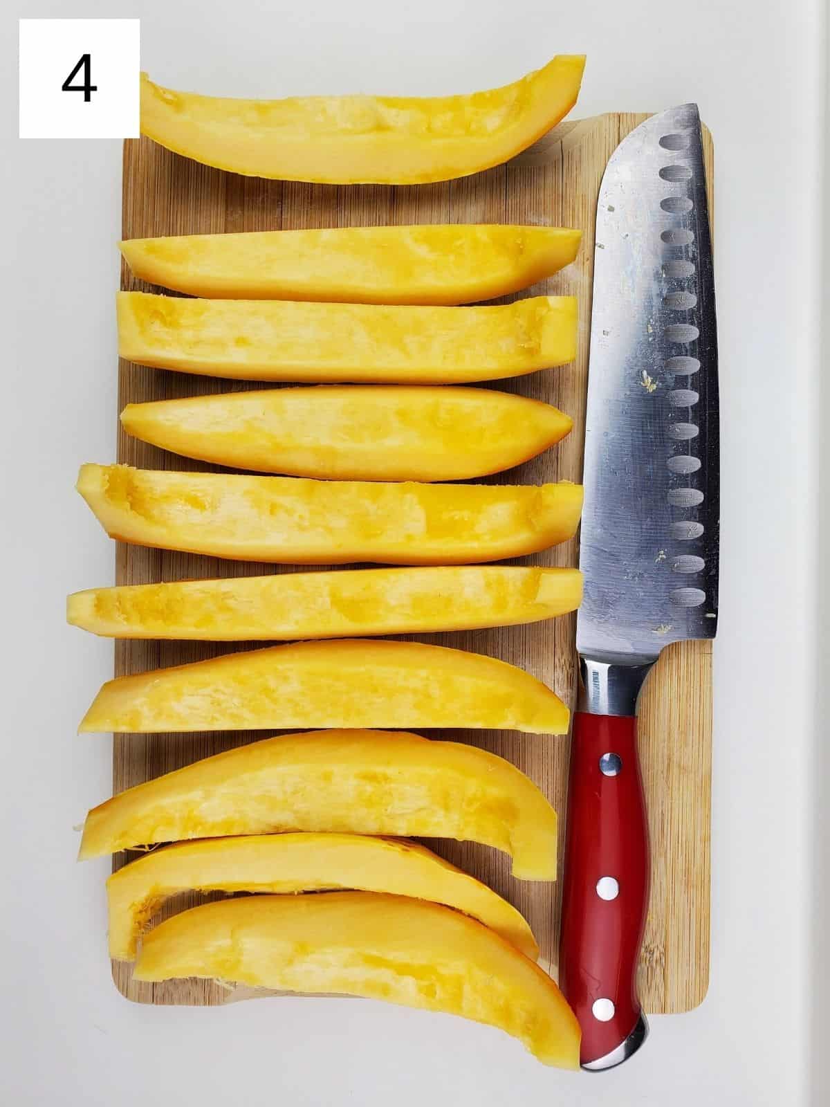 lengthwise slices of delicata squash on a wooden cutting board.