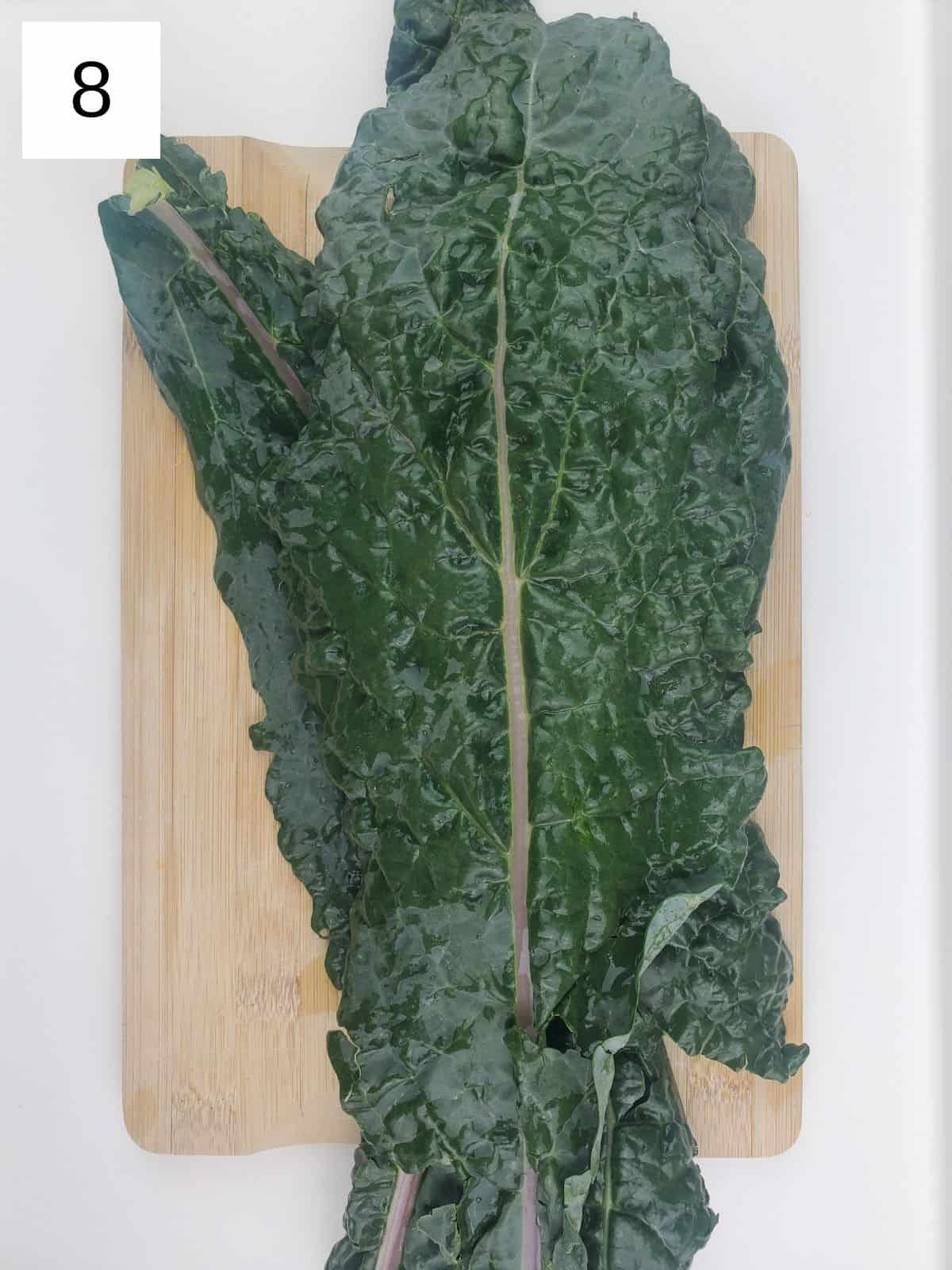 kale leaves on a wooden cutting board.