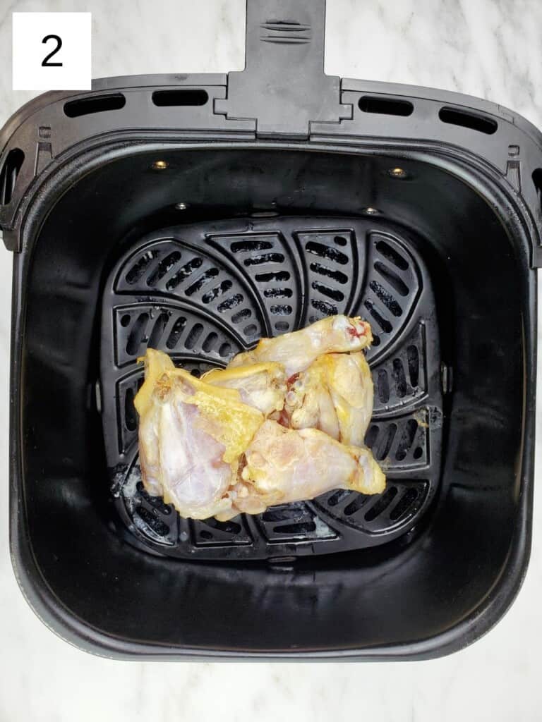 clump of defrosted chicken wings sitting in air fryer basket.