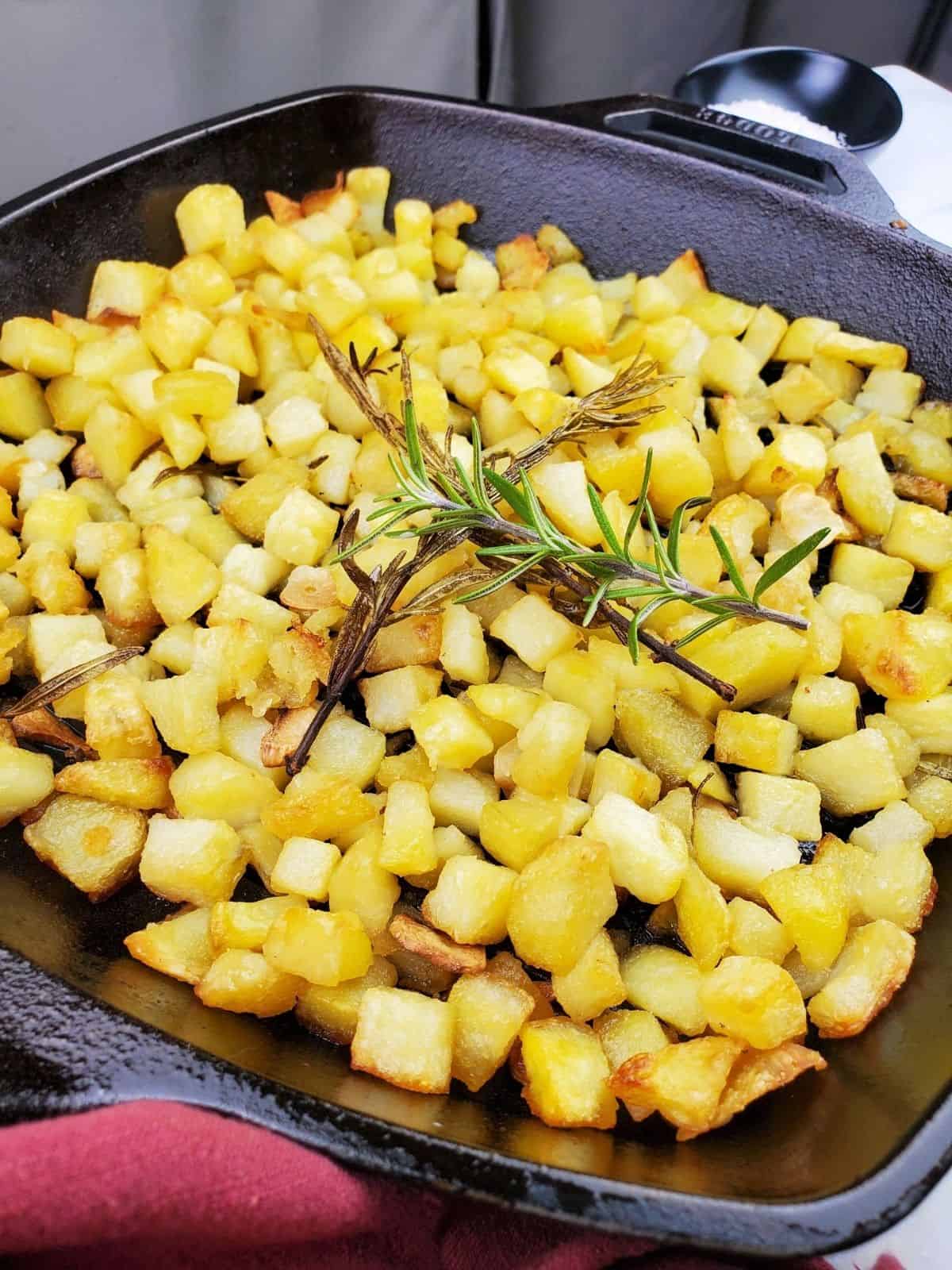 parmentier potatoes, topped with rosemary leaves, in an cast iron pan.