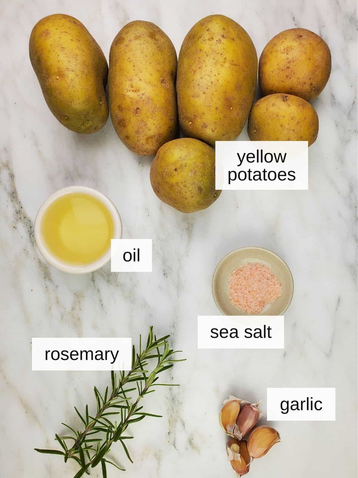ingredients for making parmentier potatoes, including yellow potatoes, oil, sea salt, rosemary, and garlic.