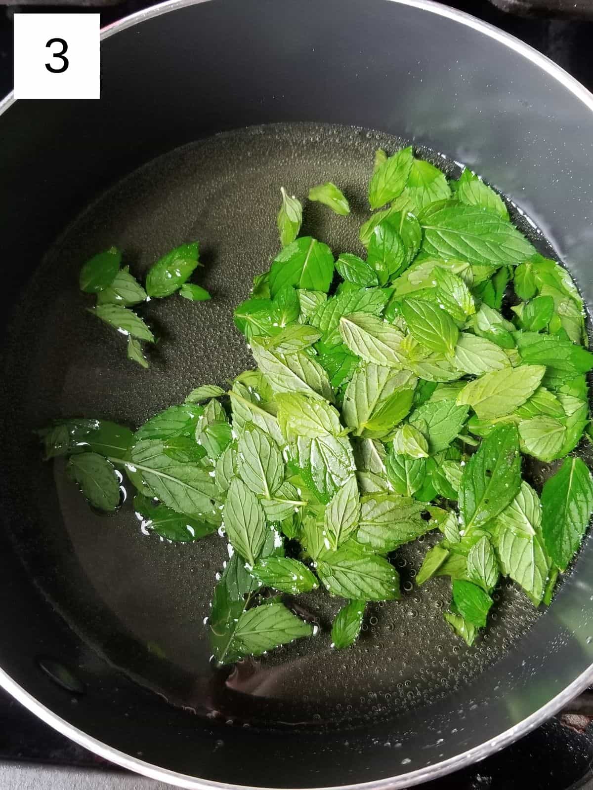 a mixture of water, allulose, and peppermint leaves in a pot.