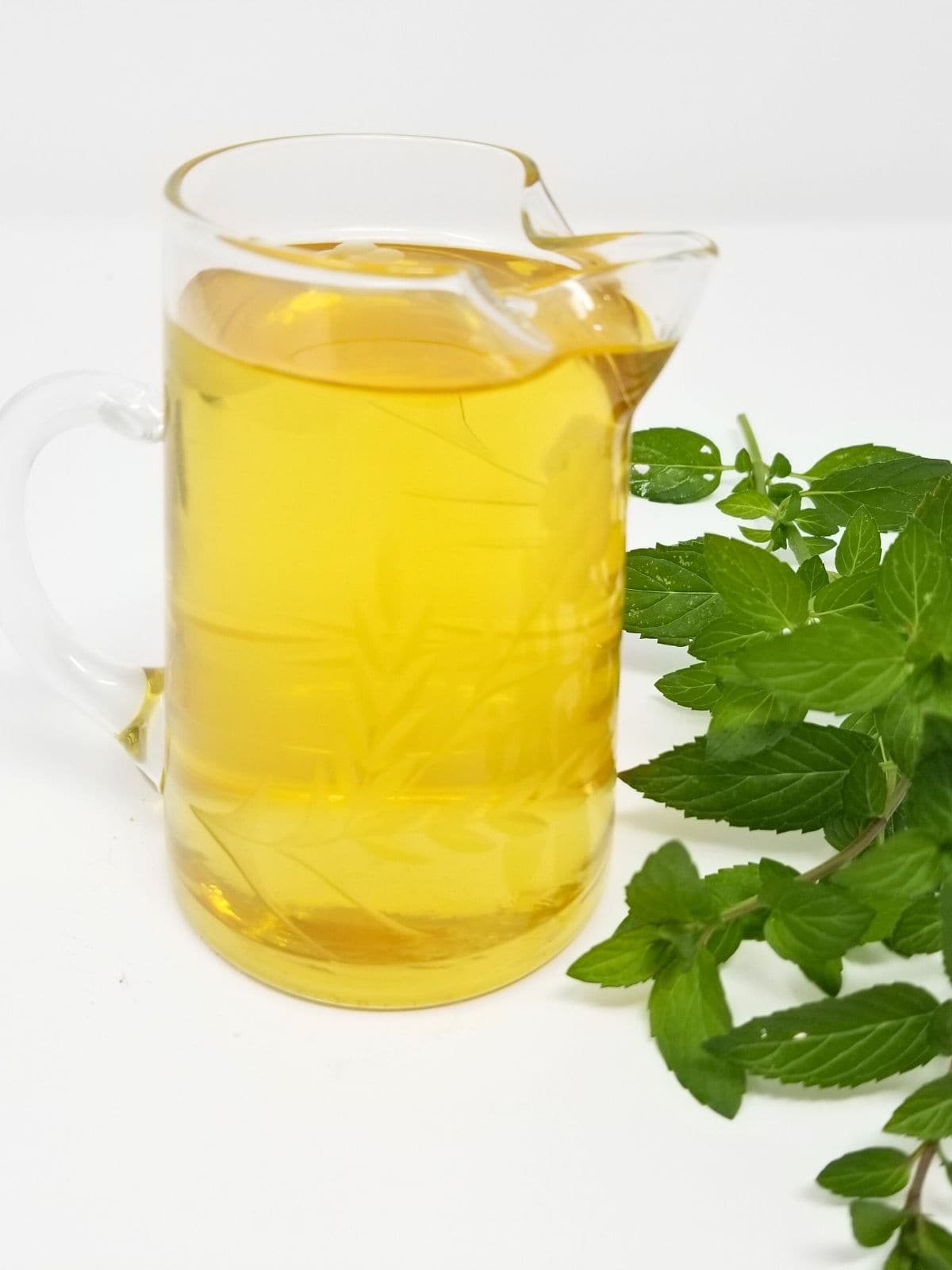 homemade peppermint syrup, made with fresh peppermint leaves, in a glass container.
