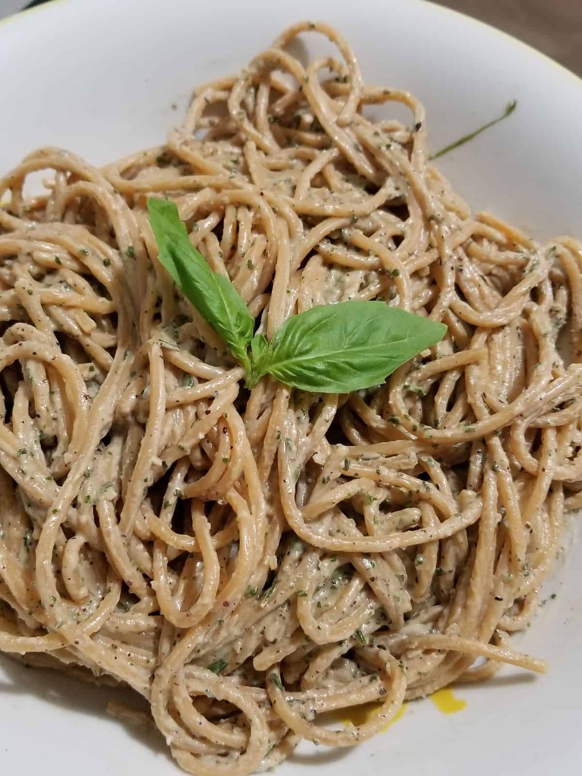 a plate of spaghetti pasta coated with garlic herb tahini sauce.