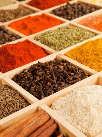 a vibrant variety of low histamine spices neatly organized on a wooden spice organizer.