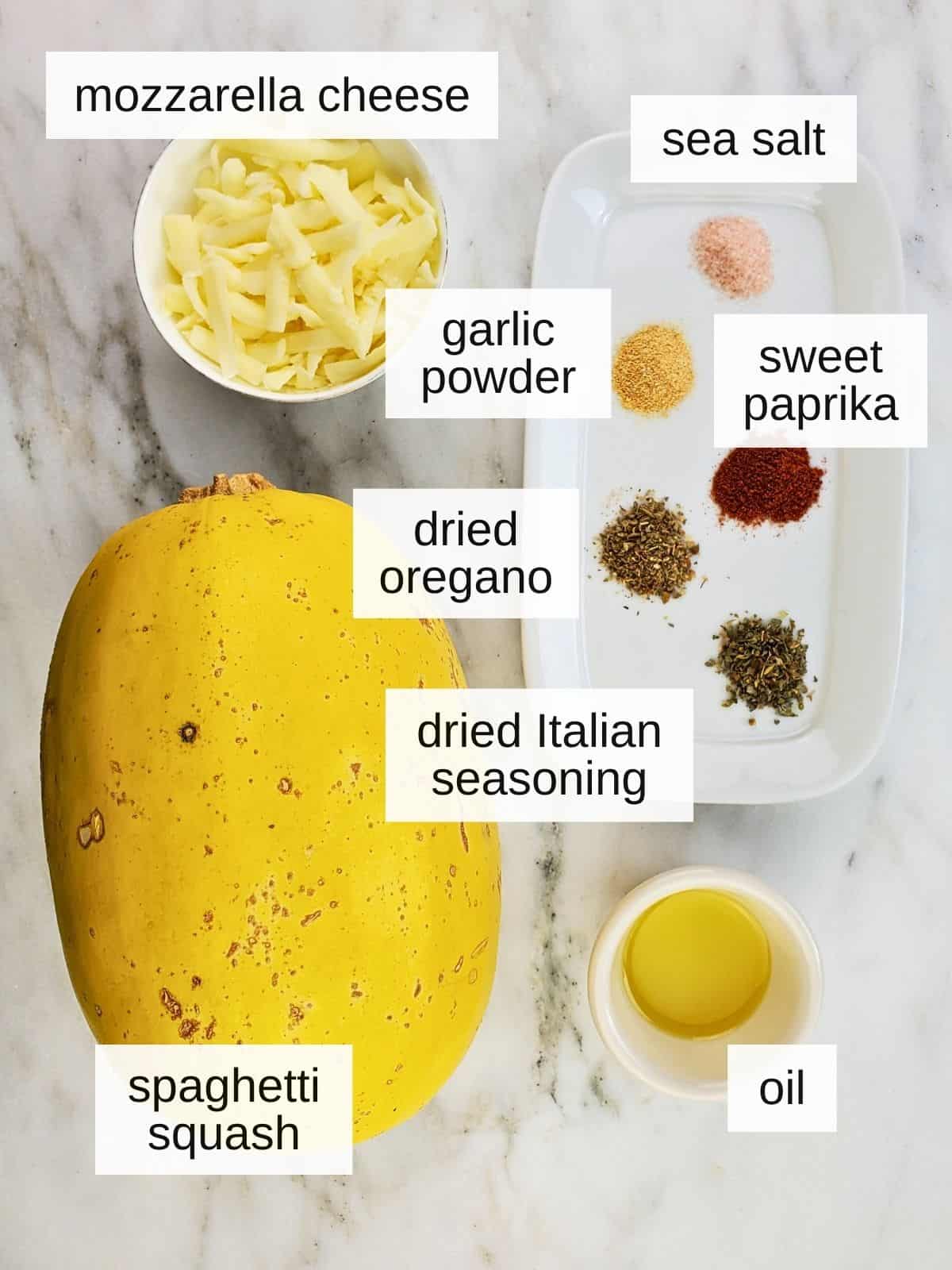 ingredients for roast spaghetti squash, including mozzarella cheese, sea salt, garlic powder, sweet paprika, dried oregano, dried Italian seasoning, oil, and spaghetti squash.