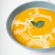 butternut squash and sweet potato soup, topped with some herbs, in a bowl.