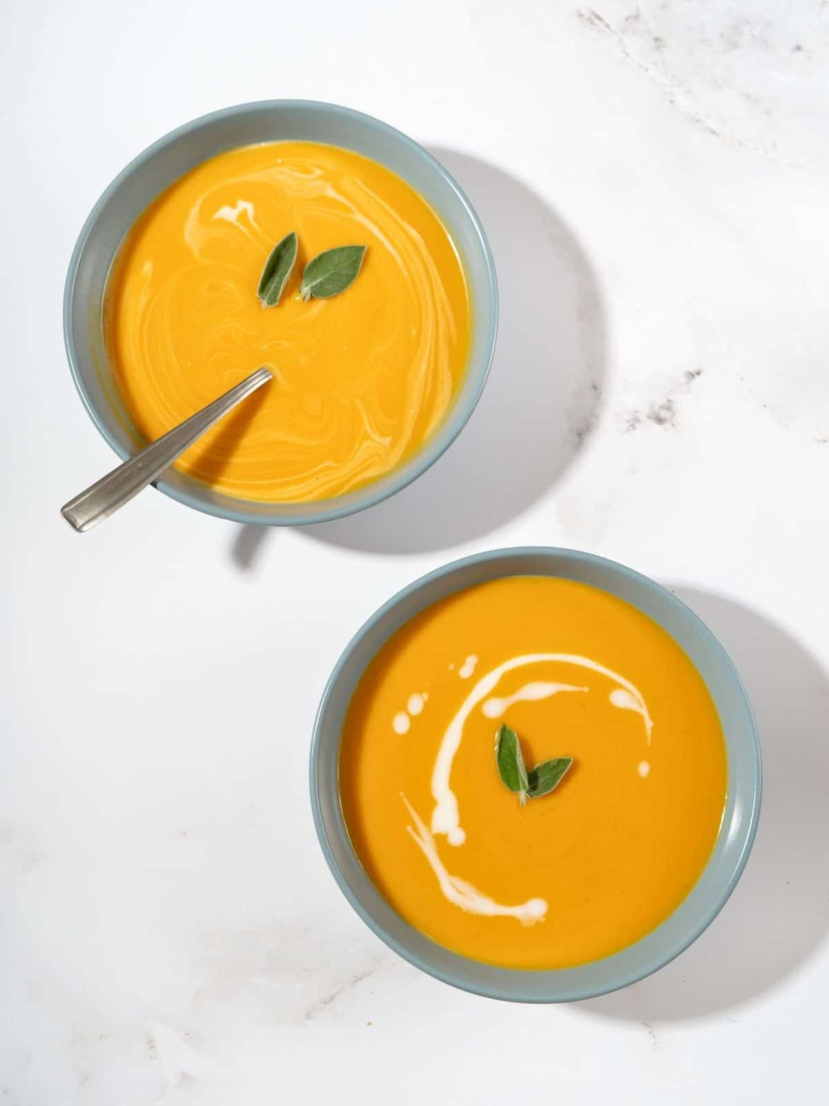 butternut squash and sweet potato soup, topped with some herbs, in a bowl.