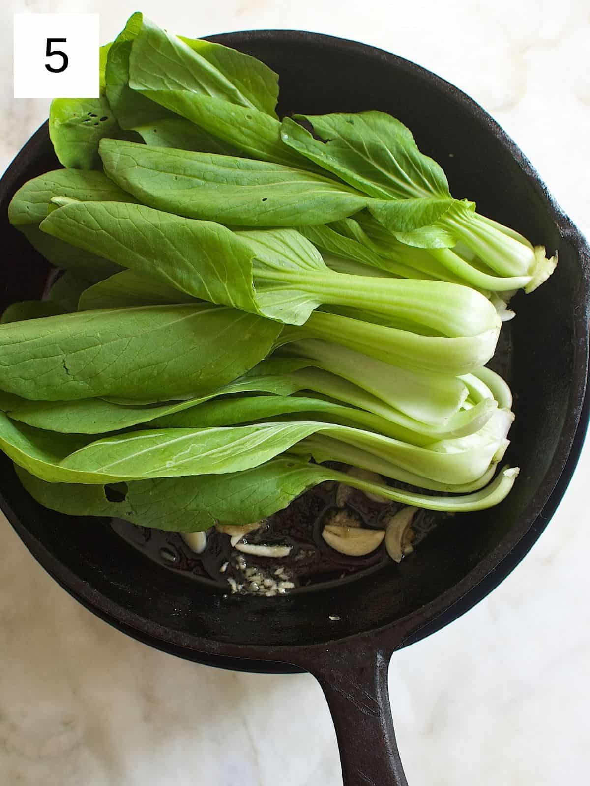 washed bok choy on a pan with sautéed garlic and ginger.