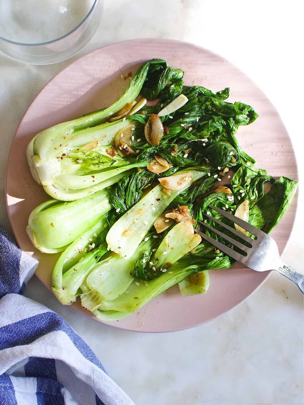 cooked bok choy, seasoned with garlic and ginger, on a plate.