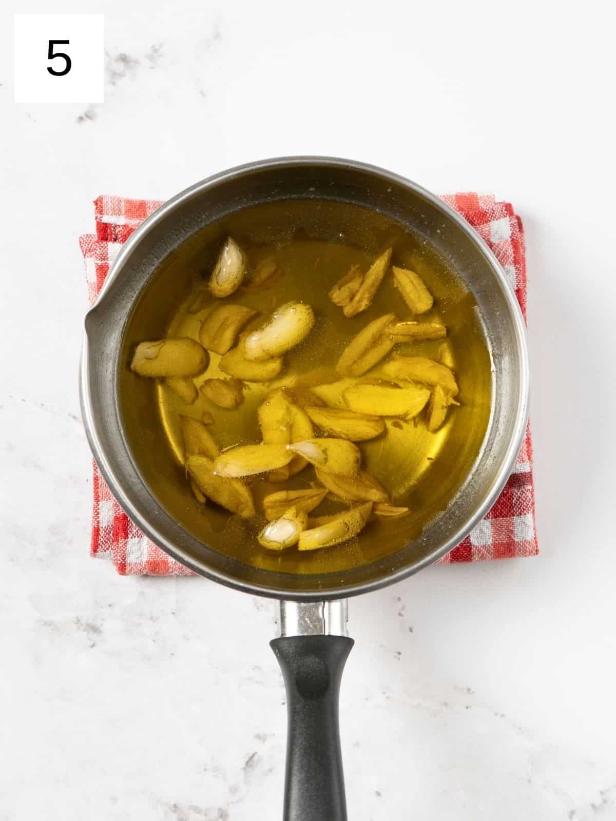 a heated pan of olive oil with garlic cloves.