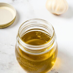 garlic-infused olive oil, made with olive oil and garlic, in a glass container.