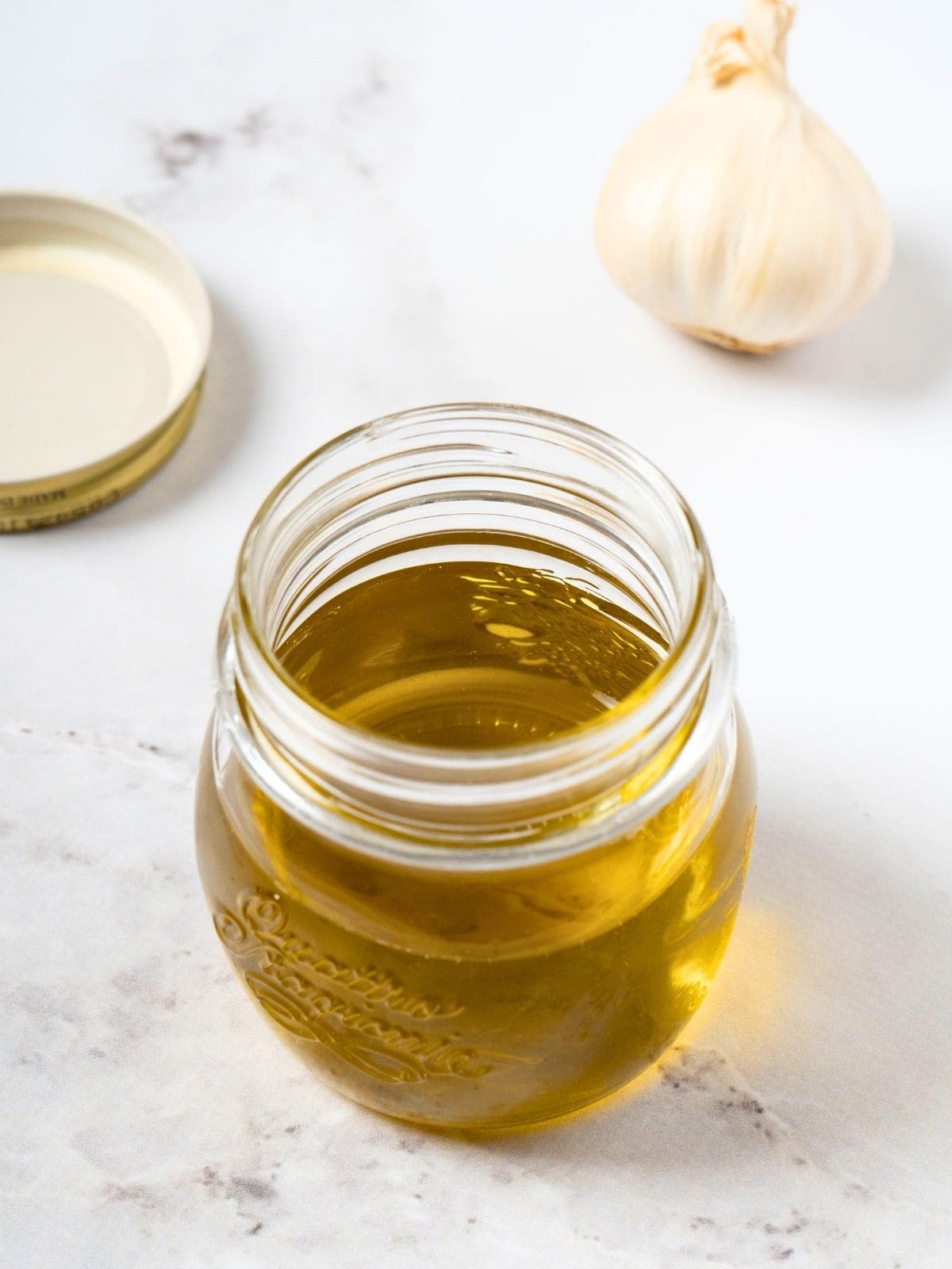 garlic-infused olive oil, made with olive oil and garlic, in a glass container.