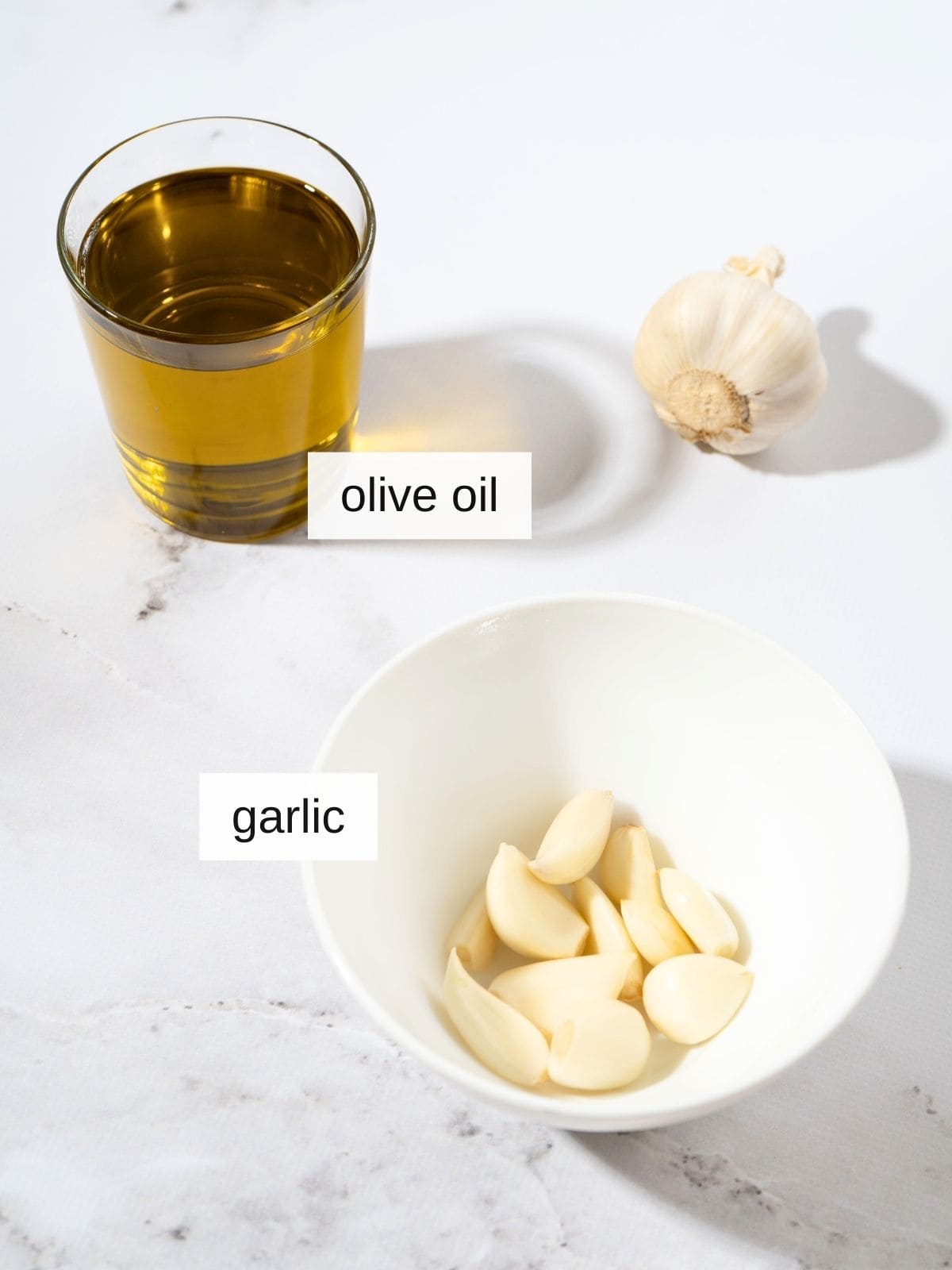 ingredients for garlic-infused olive oil recipe, including olive oil, and raw garlic cloves.