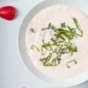 keto radish mash made with small radishes, heavy cream, and garlic, topped with some herbs, in a bowl.