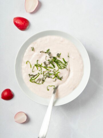 keto radish mash made with small radishes, heavy cream, and garlic, topped with some herbs, in a bowl.