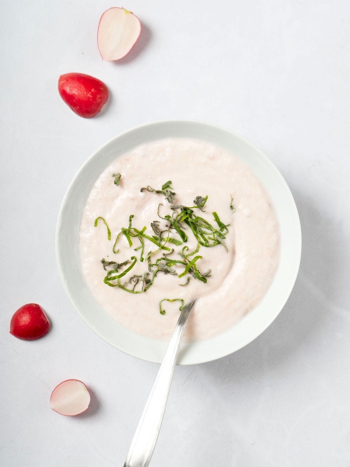 keto radish mash made with small radishes, heavy cream, and garlic, topped with some herbs, in a bowl.