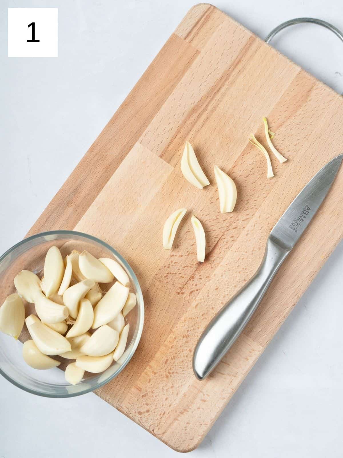 slicing the garlic cloves on a wooden chopping board.